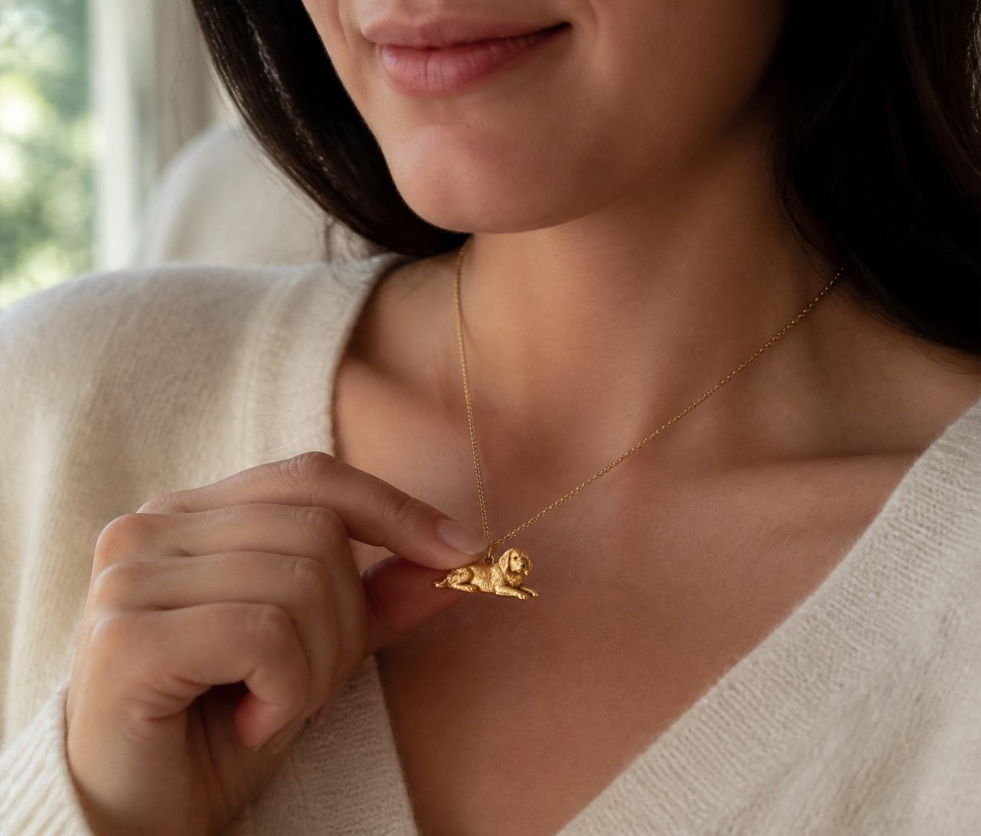 Woman in a cream sweater holding a gold pet pendant